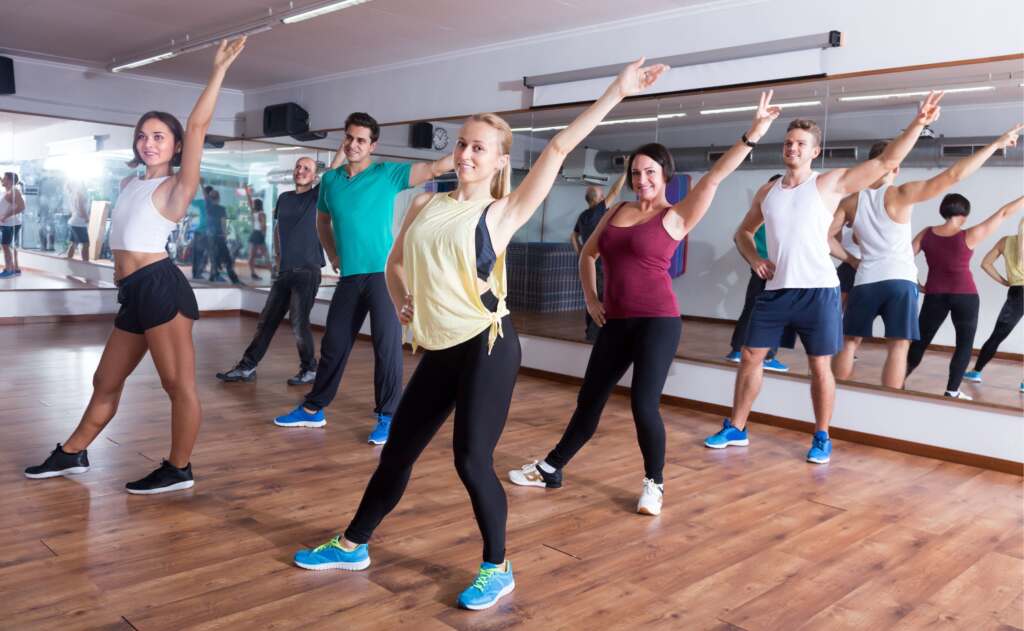 Varias personas en una clase colectiva de entrenamiento con soporte musical