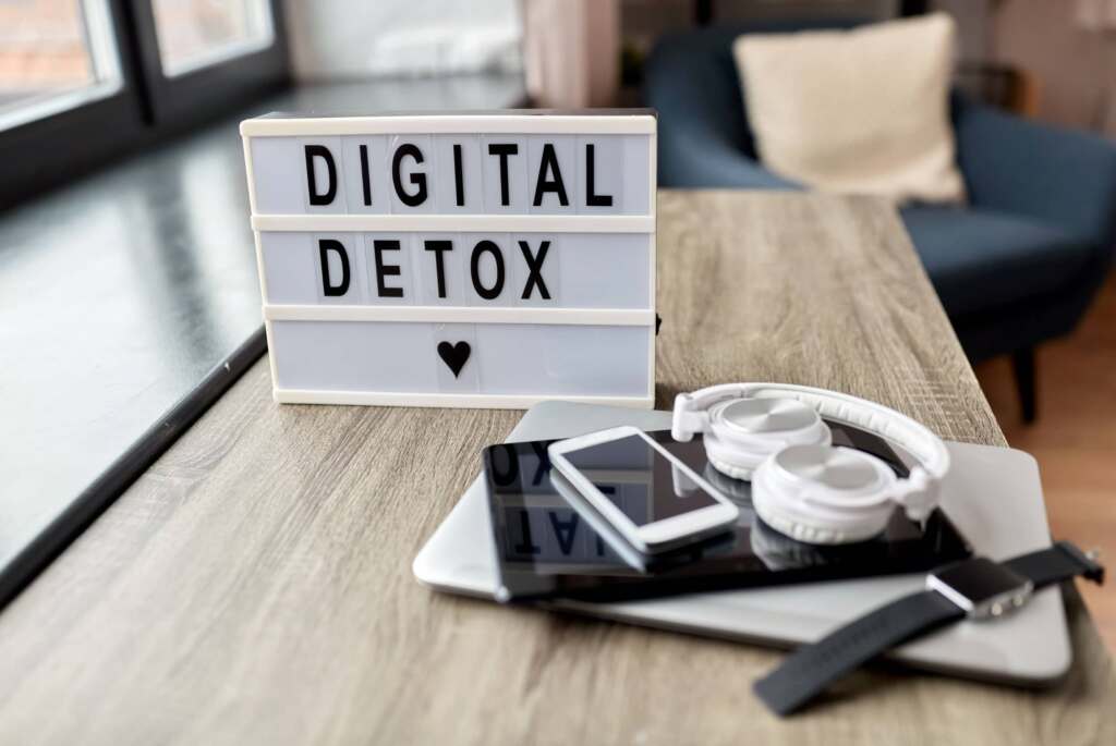Montaña de dispositivos electrónicos con cartel de Digital Detox
